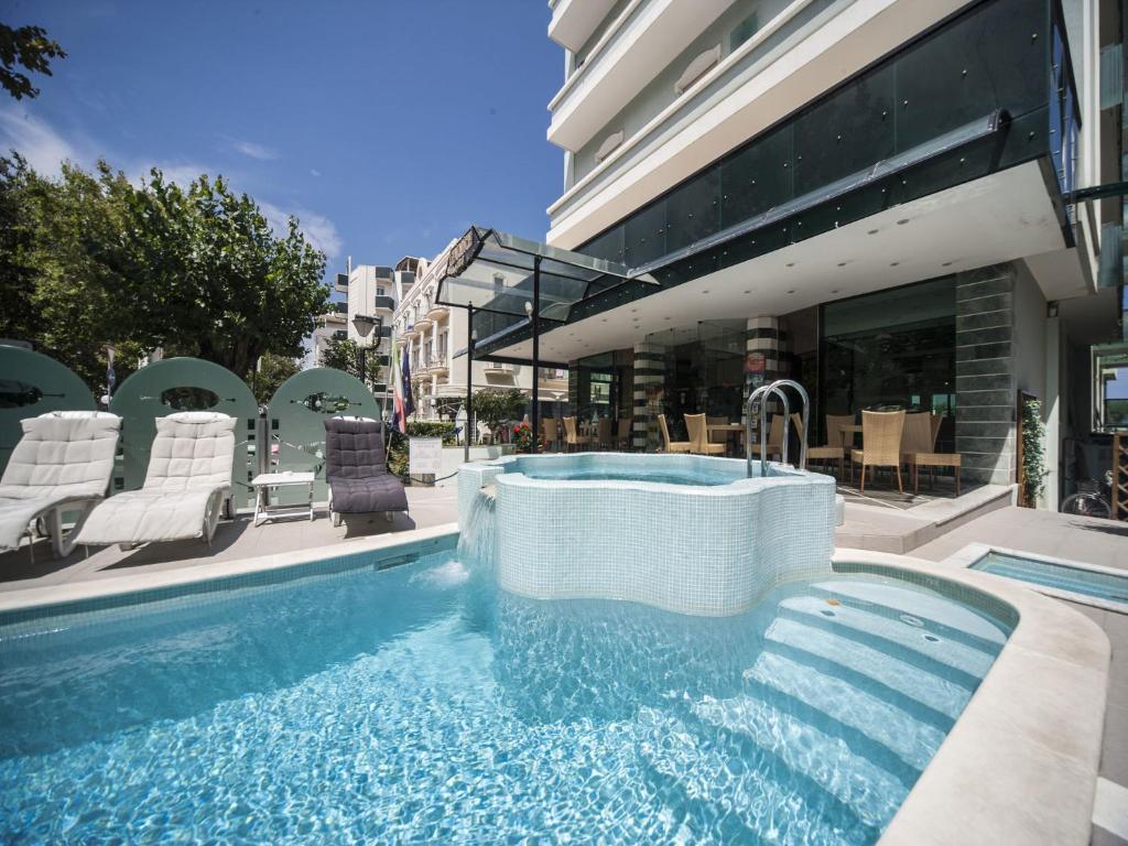 a swimming pool with a hot tub in front of a building at Hotel Levante in Rimini