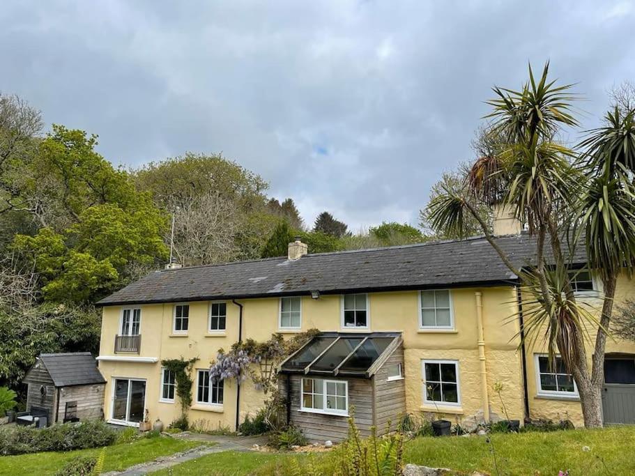a yellow house with a black roof and palm trees at Garden Room @ Bosanath Mill in Falmouth