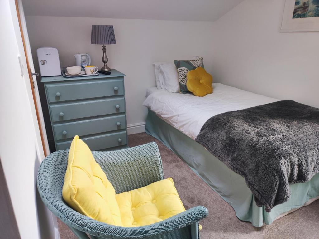 a bedroom with a bed and a chair and a dresser at Pleasant streams Barn in St Austell