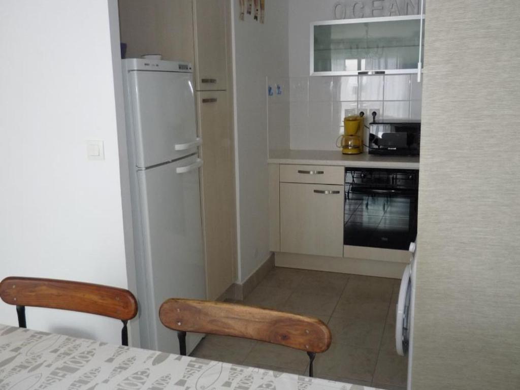 Il comprend une cuisine équipée d'un réfrigérateur blanc, d'une table et de chaises. dans l'établissement Charmant T2 avec Balcon, Parking et Accès Plage - Les Sables d'Olonne - FR-1-325-110, à Les Sables-dʼOlonne