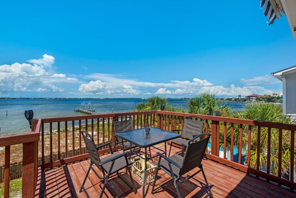 una terraza con mesa, sillas y el océano en Le Starboard House en Pensacola Beach