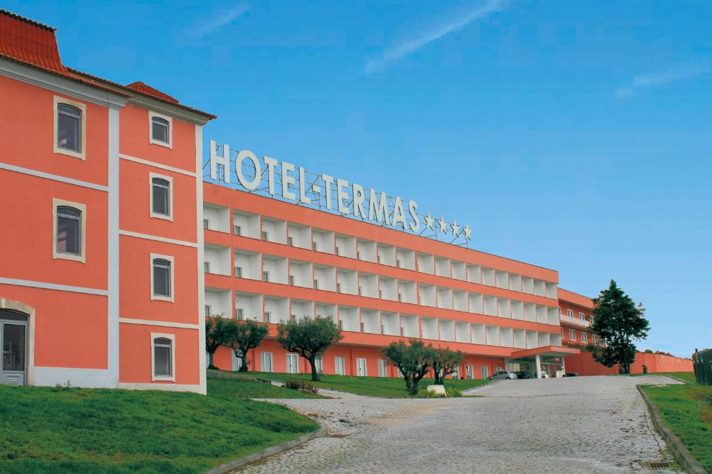 un gran edificio rojo con un cartel en él en Palace Hotel & SPA Termas do Bicanho, en Soure