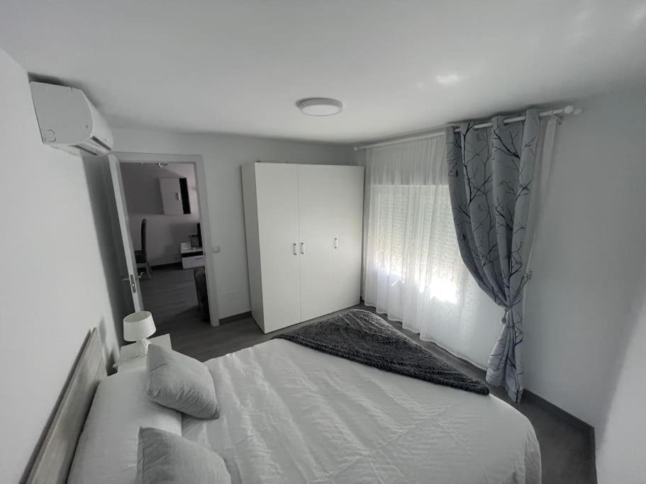 a bedroom with a white bed and a window at Tu precioso piso en el centro de Torrejón in Torrejón de Ardoz