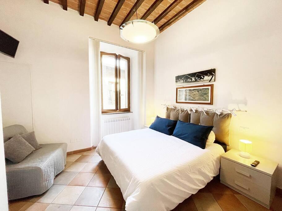 een slaapkamer met een groot wit bed en een bank bij Casa Montanini Centro Storico in Siena