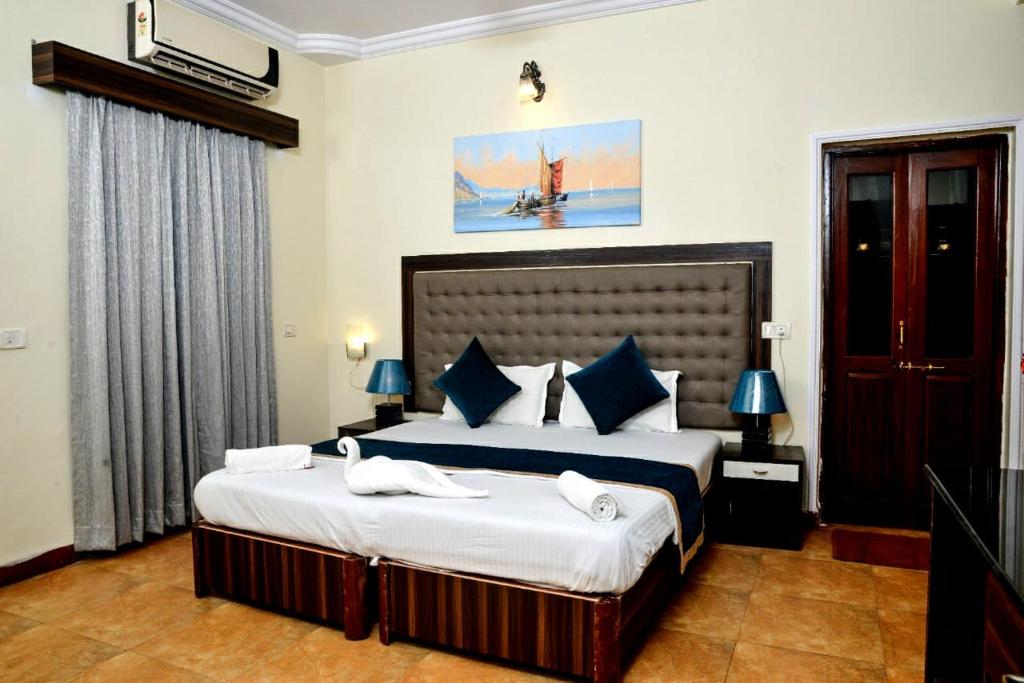 a bedroom with two beds with white sheets and blue pillows at Lucianas Beach Resort in Marmagao