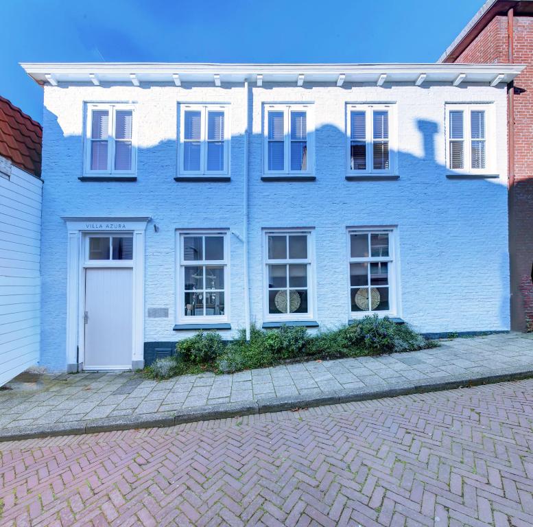 a blue house with a white door on a brick street at Villa Azura in Tholen