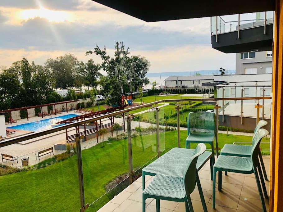 einen Balkon mit Stühlen, einem Tisch und einem Pool in der Unterkunft Admiral Lakeside Luxury Apartment in Siófok