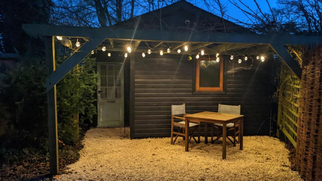 A Somerset Countryside Lodge في Holcombe: طاولة وكراسي أمام كوخ في الليل
