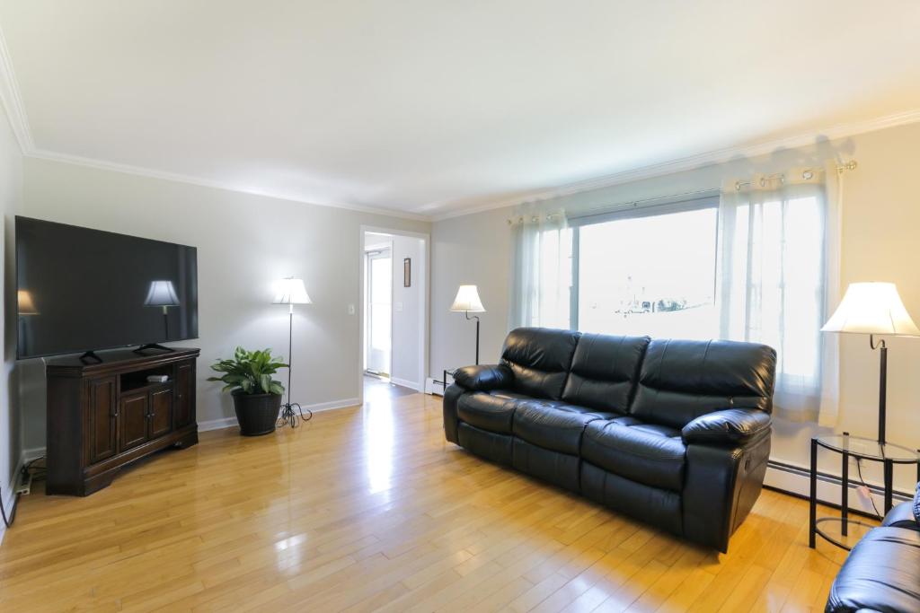 sala de estar con sofá de cuero negro y TV en Connecticut Vacation Home Rental with Private Pool! en Southington