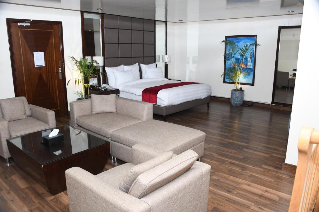 a hotel room with a bed and a couch and chairs at Rockville House managed & operated by Serai Boutique Hotels and Resorts in Islamabad