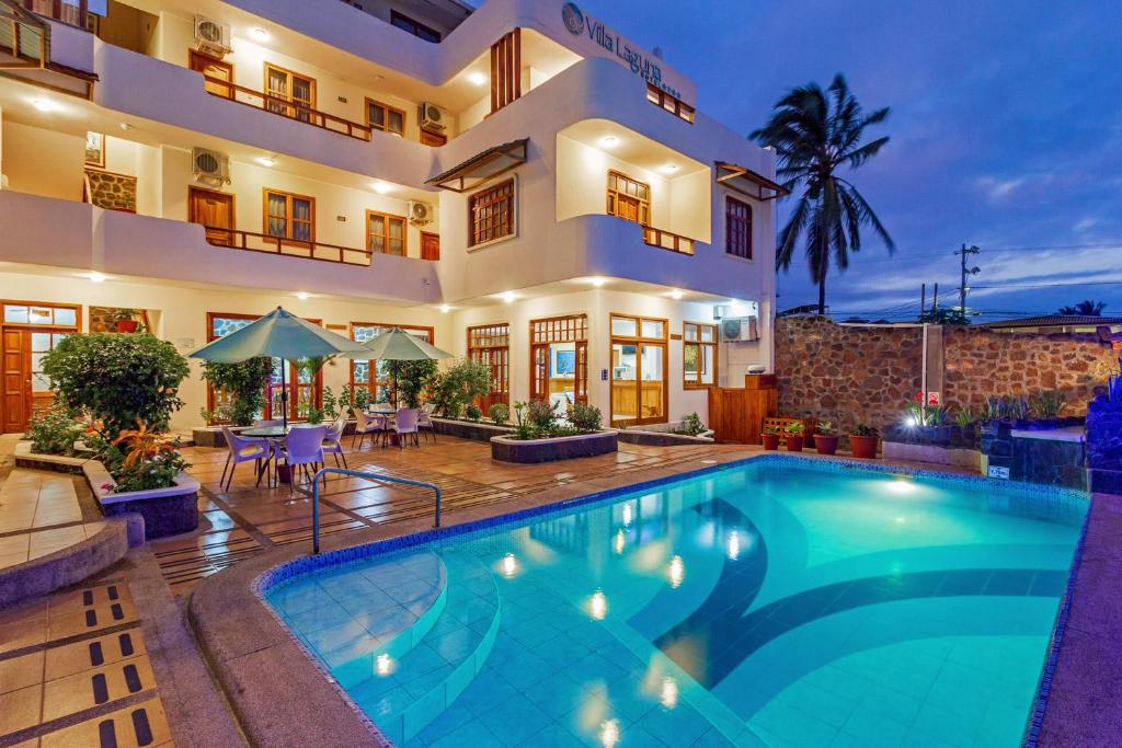 a villa with a swimming pool in front of a house at Hotel Villa Laguna in Puerto Ayora