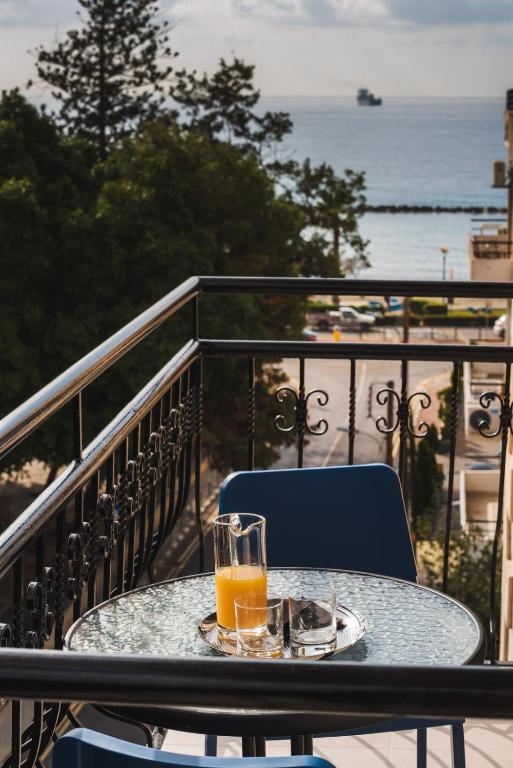 a glass of orange juice sitting on a table on a balcony at Chrielka Hotel in Limassol