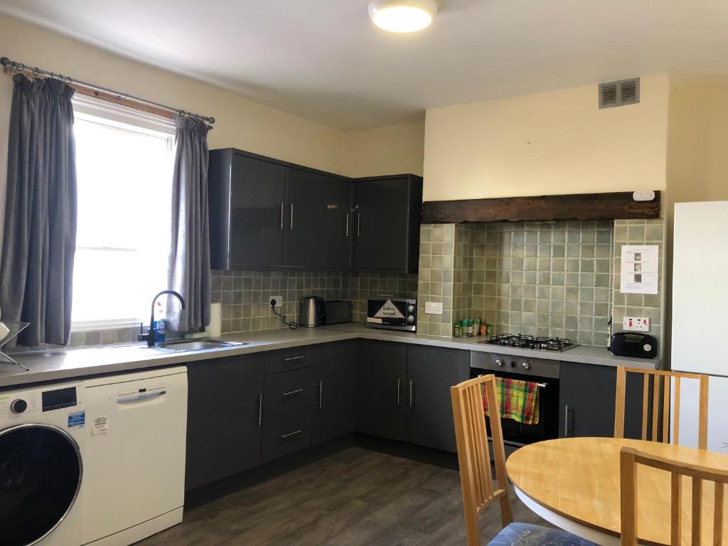 a kitchen with black cabinets and a table and a window at Comfortable home, town centre, free parking,Multiple Rooms in Cheltenham