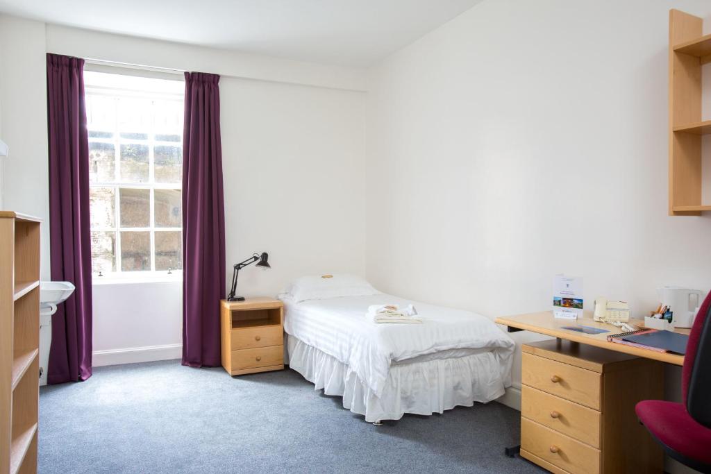 a bedroom with a bed and a desk and a window at McIntosh Hall Campus Accommodation in St Andrews