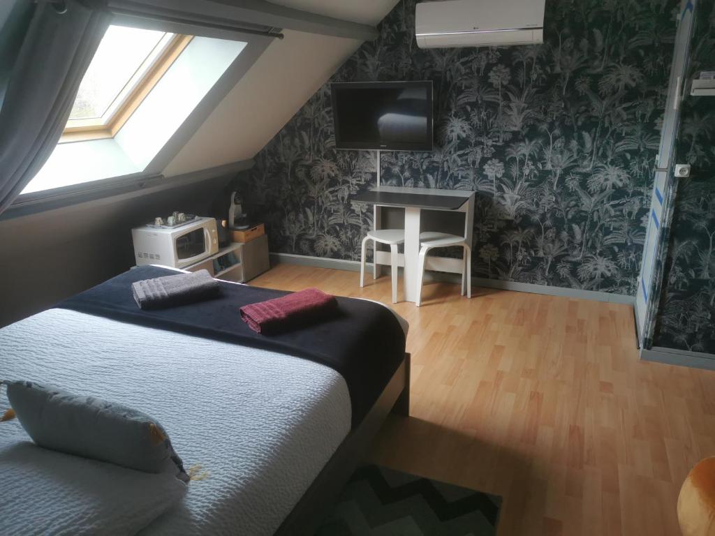 een slaapkamer met 2 bedden, een tv en een bureau bij Agréable chambre d’hôte à la campagne in Villefranche-Sur-Cher