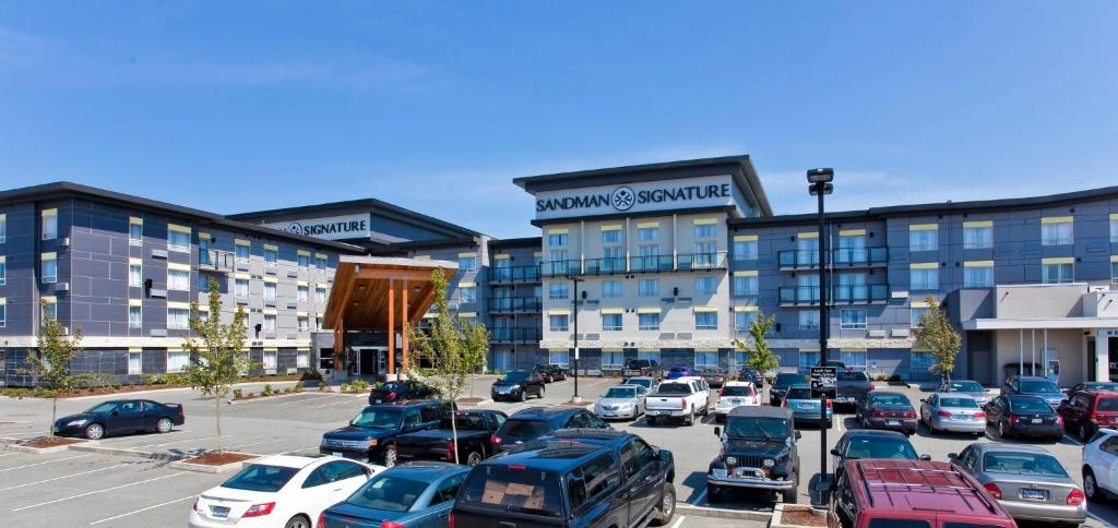 a parking lot with cars parked in front of a building at Sandman Signature Langley Hotel in Langley