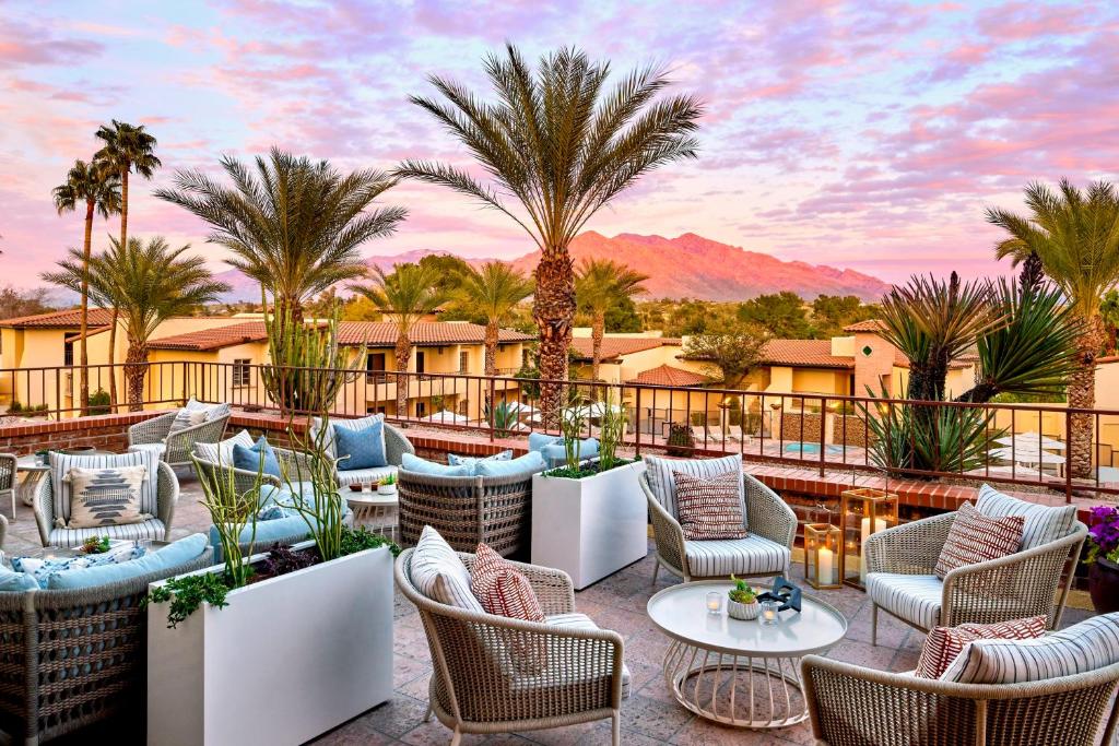 d'une terrasse avec des chaises, des tables et des palmiers. dans l'établissement Omni Tucson National Resort, à Tucson