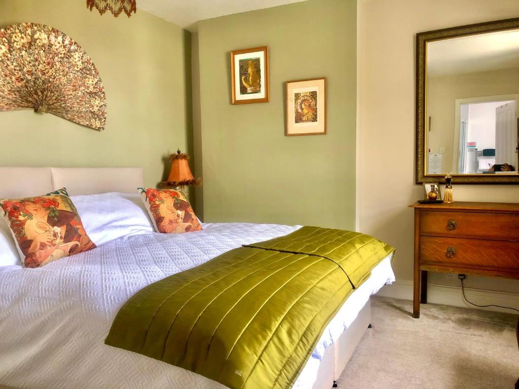 a bedroom with a bed with a mirror and a dresser at Mulberry House in Llandudno