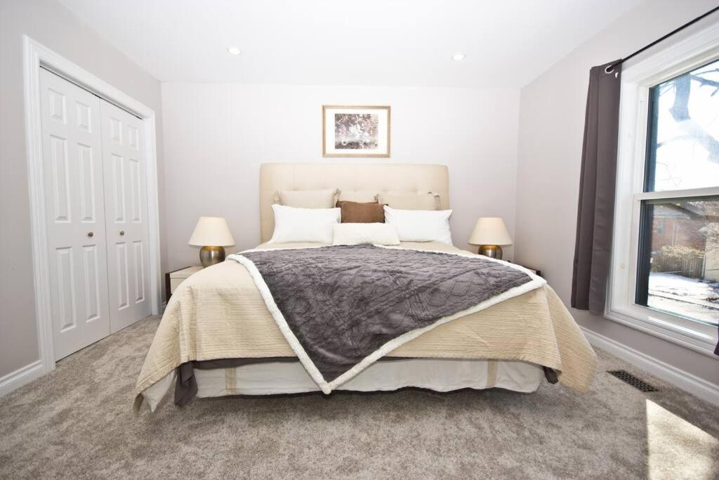 ein Schlafzimmer mit einem Bett, zwei Lampen und einem Fenster in der Unterkunft Stylish Home For A Perfect Stay for 4! in Peterborough