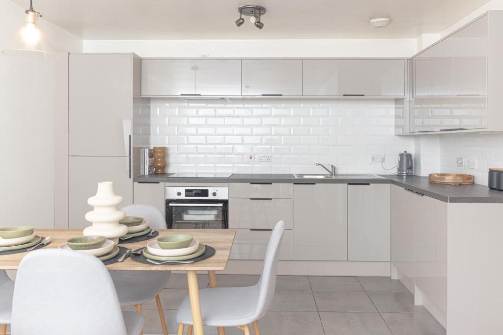 Hotel Luxury Apartment, Birmingham-Parking, a kitchen with white cabinets and a wooden table with chairs at Luxury Apartment, Birmingham-Parking in Birmingham