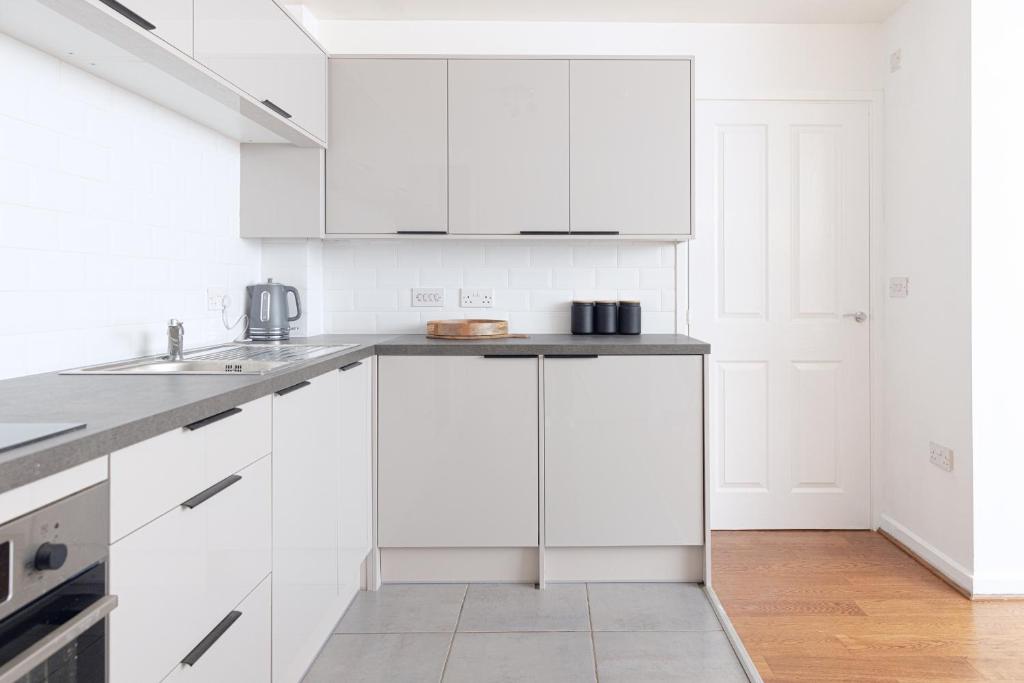 a white kitchen with white cabinets and a sink at Luxury Apartment, Birmingham-Parking in Birmingham