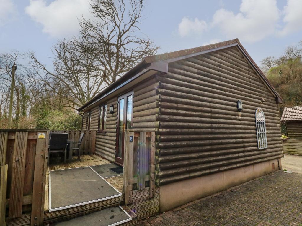 uma cabina de madeira com uma porta e uma cerca em Chalet Log Cabin L2 em Ilfracombe