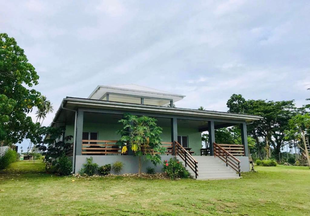 a small house with a porch and a grass field at La Maison Hebridaise in Luganville