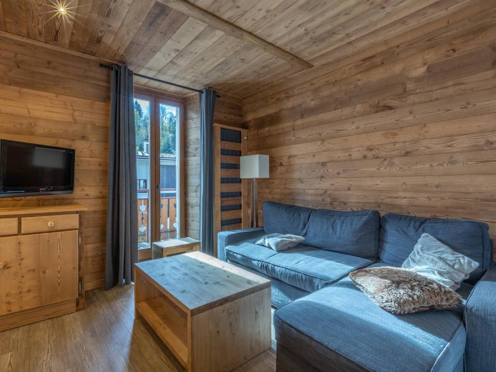 ein Wohnzimmer mit einem blauen Sofa und einem TV in der Unterkunft Appartement La Clusaz, 4 pièces, 8 personnes - FR-1-437-48 in La Clusaz