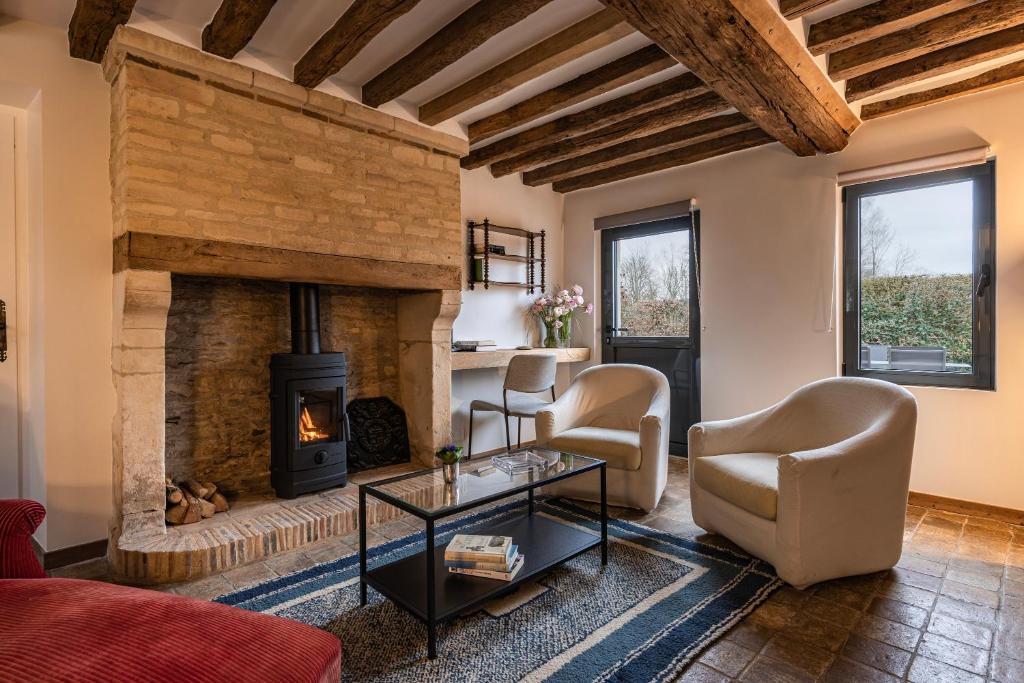 a living room with a stone fireplace and two chairs at La Maison Cornière in Biéville-en-Auge