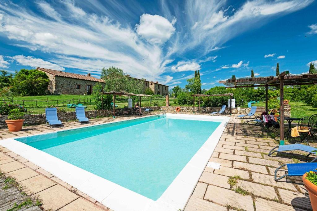a swimming pool with chairs and a house at Agriturismo Fattoria di Statiano in Pomarance