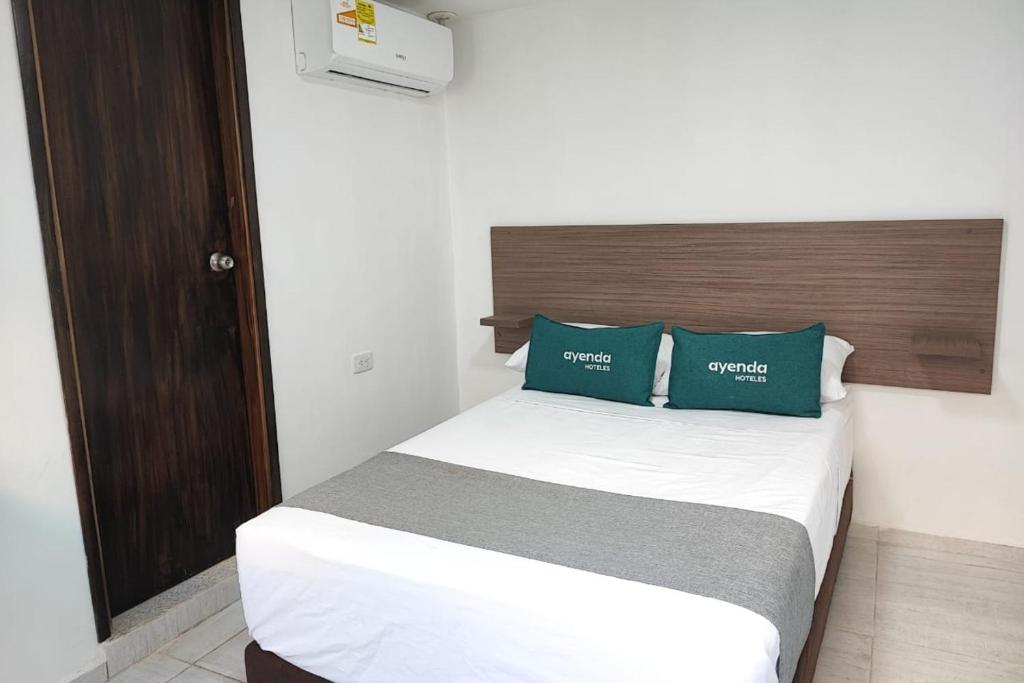 1 dormitorio con 1 cama con 2 almohadas verdes en Ayenda Hotel Helenas, en Ríohacha