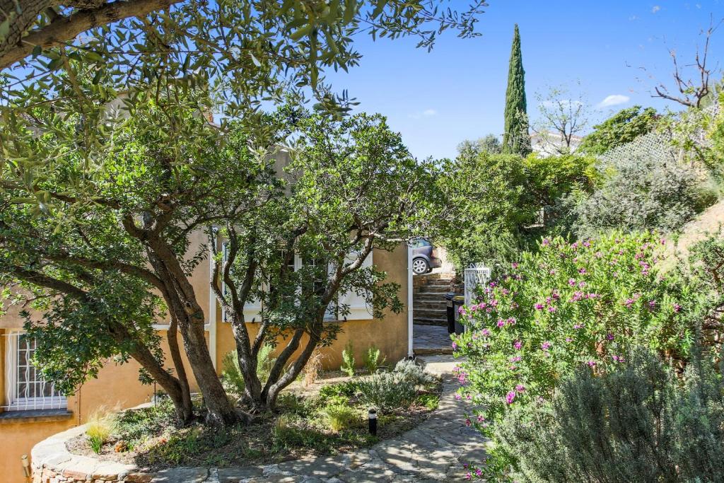 a garden with trees and flowers in front of a building at Maison du Baou - Welkeys in Toulon