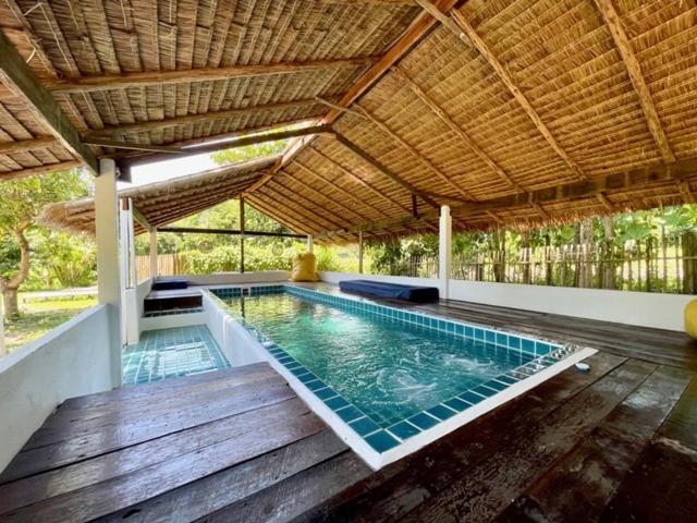 an indoor swimming pool with a wooden floor and a roof at La Maison - Chiangmai in Mae Taeng