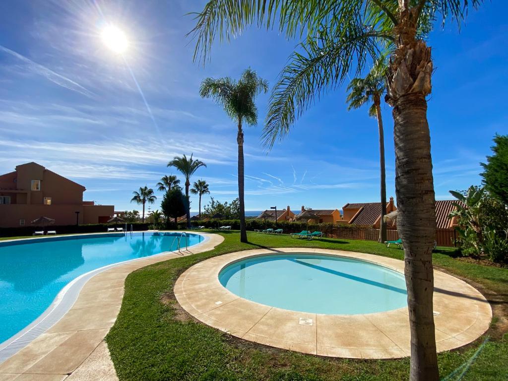 uma piscina com palmeiras em redor em Marbella Elviria apartment em Marbella