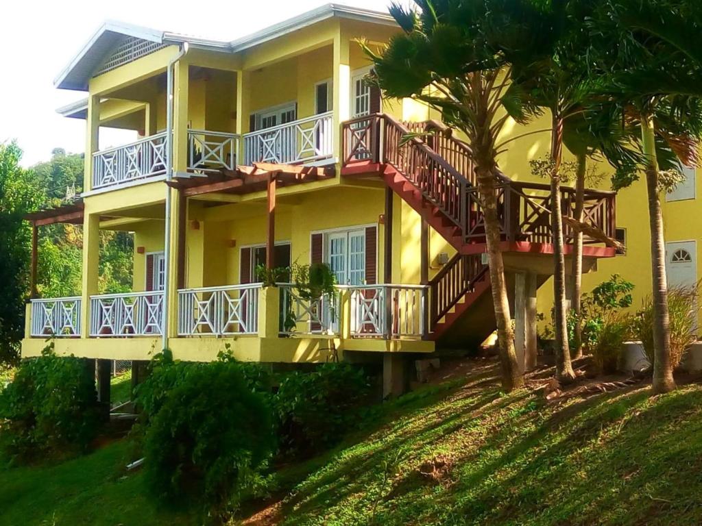 a yellow house with a balcony and palm trees at Seascape Villa 2BR with Stunning Caribbean Sea View in Charlotte
