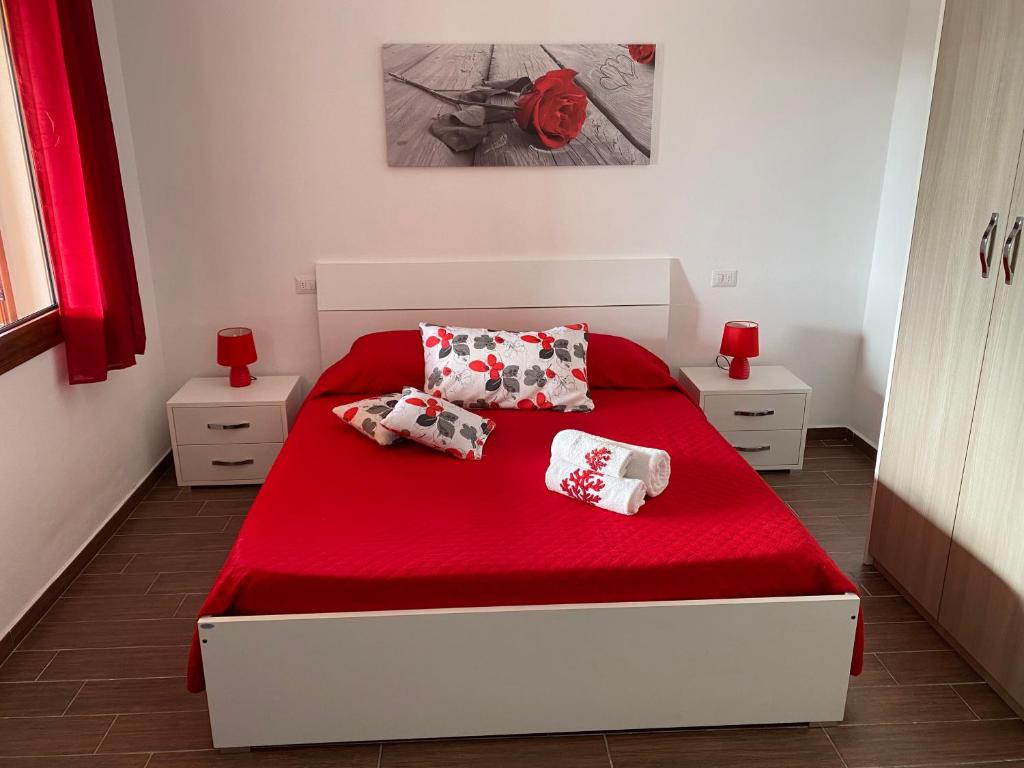 ein Schlafzimmer mit einem roten Bett mit roten Laken und Kissen in der Unterkunft Villetta Capo Comino 500 m DAL MARE in Siniscola
