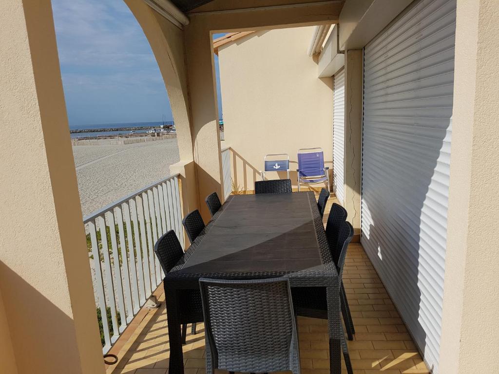 balkon ze stołem i krzesłami na plaży w obiekcie CARNON - T4 1ére ligne w mieście Mauguio