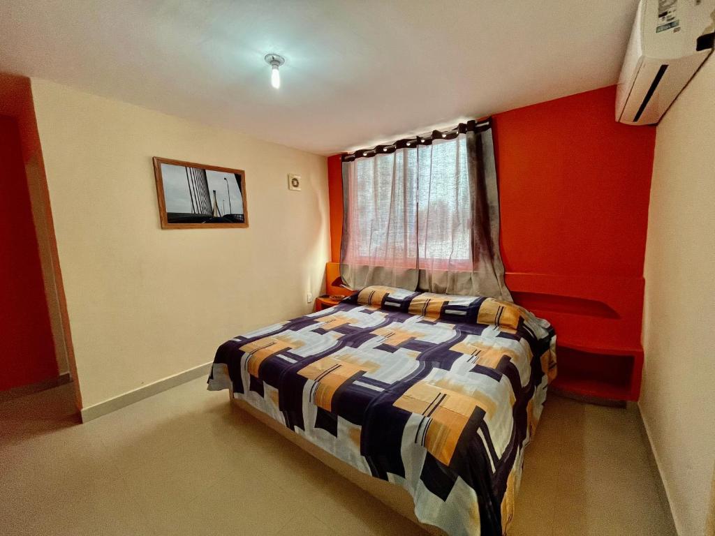 een slaapkamer met een bed met rode muren en een raam bij OYO Hotel Puerto Real Coatzacoalcos in Coatzacoalcos