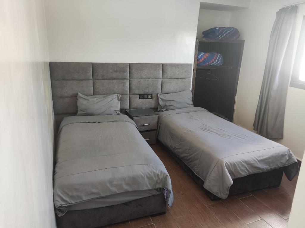 1 dormitorio con 2 camas y cabecero en Hôtel Assaâda en Rabat