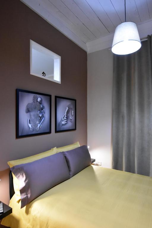 a bedroom with a yellow bed with three pictures on the wall at Kosentia Bed and Breakfast in Cosenza