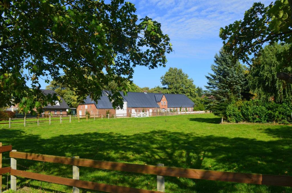 a farm with a fence and a field with houses at Hof Diederichs in Bohmstedt
