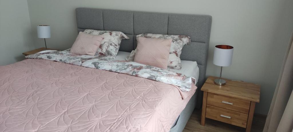 um quarto com uma cama com lençóis e almofadas cor-de-rosa em Apartaments - Liepu iela em Liepāja