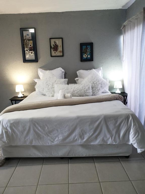 - une chambre avec un grand lit blanc et des oreillers blancs dans l'établissement Tsamatiku Villa Guesthouse, à Hazyview