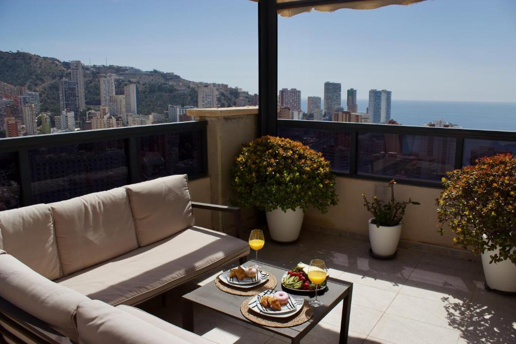 a balcony with a couch and a table with food on it at LUXURY Residence Gemelos 26 in Benidorm