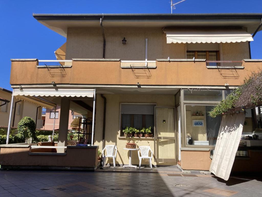 a building with two white chairs and a patio at Villetta Girasole in Torre del Lago Puccini