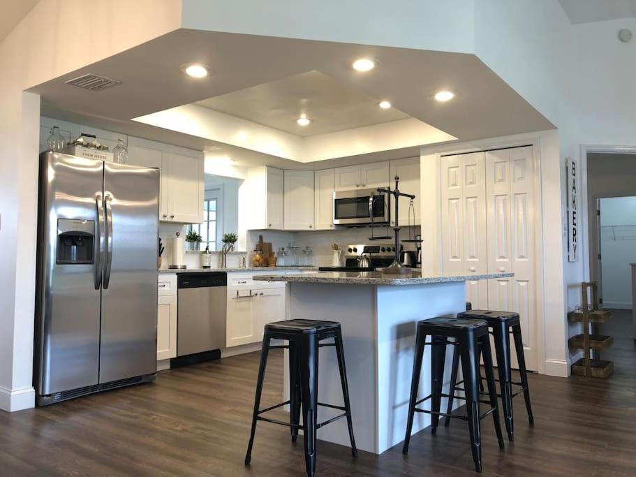 a kitchen with a stainless steel refrigerator and bar stools at Beautiful Home across the street from Lake June! in Lake Placid