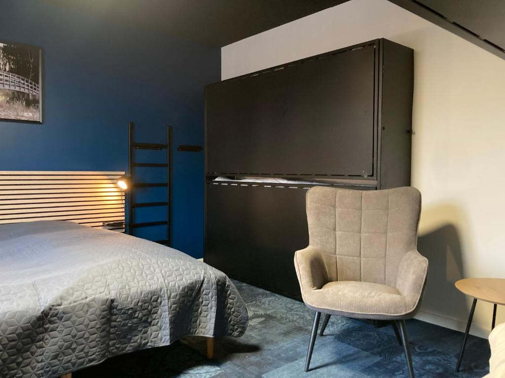 een slaapkamer met een bed en een stoel en een tv bij Signinn in Varde