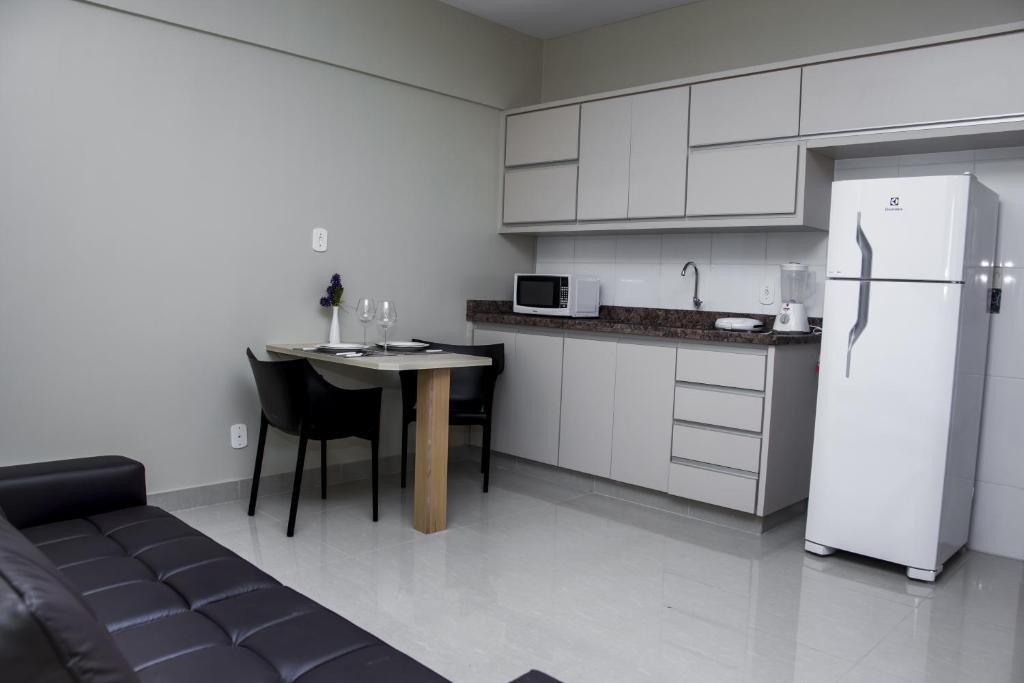 a kitchen with a table and a white refrigerator at Executivo Flat 1 in Parauapebas