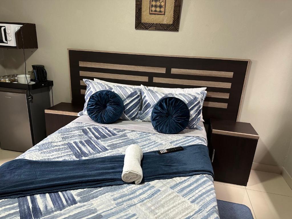 a bedroom with a bed with blue pillows at The Hide in Roodepoort in Roodepoort