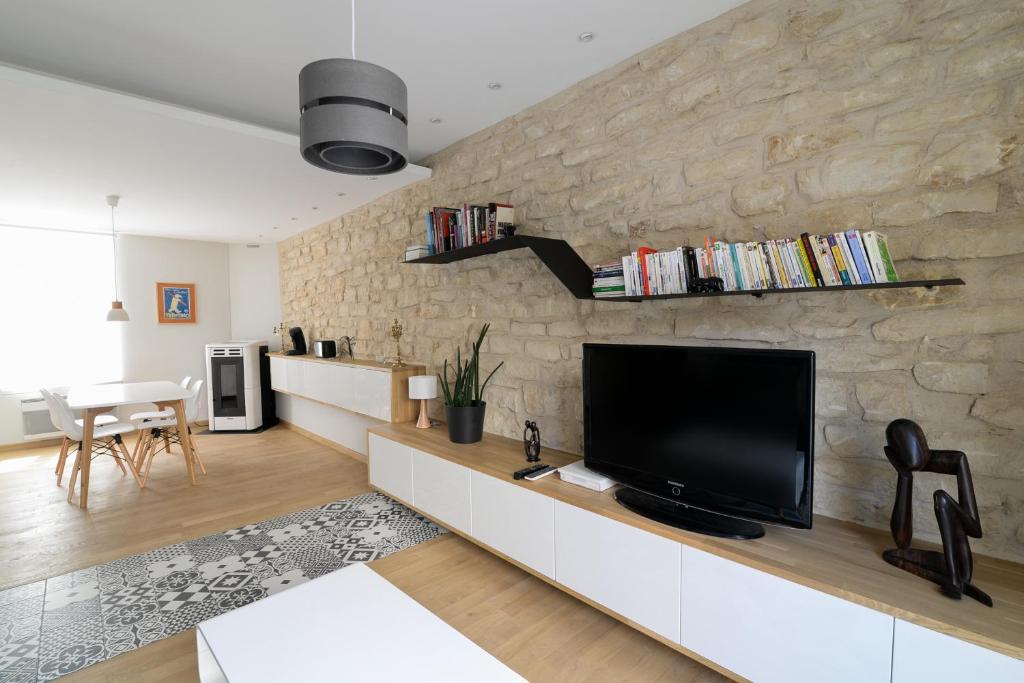 a living room with a flat screen tv on a stone wall at - Résidence Martimprey ! - in Nancy